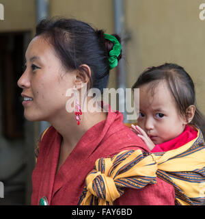 Una donna che porta una bambina sulla sua schiena; Paro, Bhutan Foto Stock