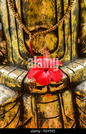 Indonesia, Tejakula, Bali, fiori di ibisco sulla statua di Buddha Foto Stock