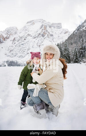 Inverno all'aperto può essere favola-maker per bambini o anche per adulti. Felice la madre e il bambino a giocare all'aperto di fronte snowy mo Foto Stock