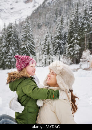 Inverno all'aperto può essere favola-maker per bambini o anche per adulti. Felice la madre e il bambino a giocare all'aperto di fronte snowy mo Foto Stock
