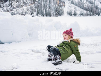 Inverno all'aperto può essere favola-maker per bambini o anche per adulti. Bambino felice nel manto verde è caduto mentre giocare nella neve. Foto Stock