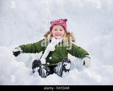 Inverno all'aperto può essere favola-maker per bambini o anche per adulti. Bambino felice nel manto verde seduto sulla neve. Foto Stock