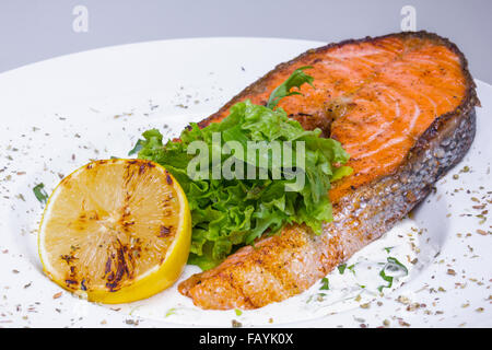 Salmone alla griglia bistecca con spinaci in piastra bianca, primo piano Foto Stock