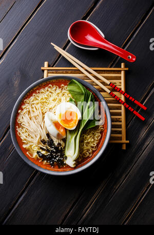 Miso Ramen Asian tagliatelle all'uovo, enoki e pak choi cavolo su scuro dello sfondo in legno Foto Stock