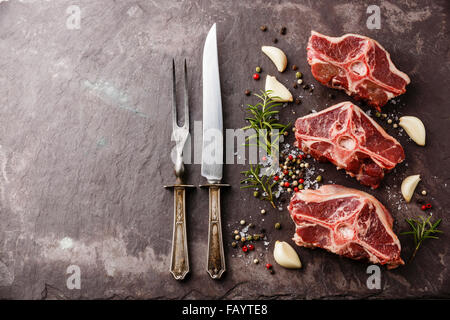 Crudo fresco di carne di agnello castrato sella con erbe e spezie su pietra piastra di ardesia Foto Stock