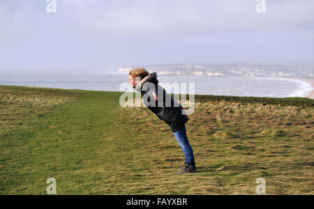 La donna fatica a stare in piedi in venti alti sulla parte superiore della testa di Seaford scogliere in East Sussex parte del South Downs Way Foto Stock