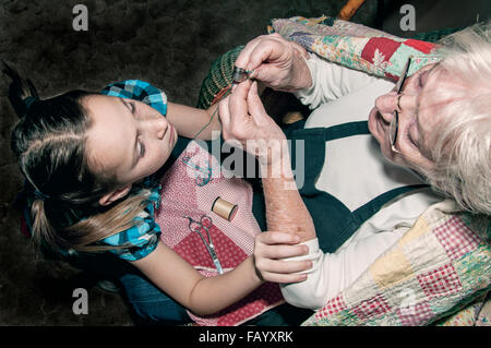 Ragazza con nonne mani stabilizzata con un ago di filettatura Foto Stock