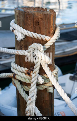 Frammento di cima nautica recinto con legno stagionato post nel porto di Key West, Florida, barche ancorate in background. Foto Stock