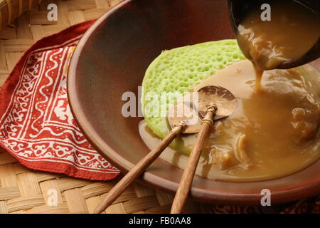 Durian Serabi, latte di cocco pancake serviti con palm salsa di zucchero con aggiunta di durian. Placcato su stoviglie di terracotta. Foto Stock