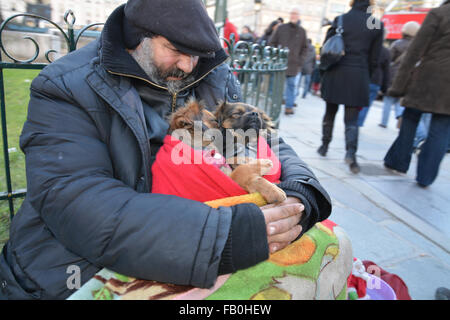 Un uomo senza tetto in corrispondenza dei gradini della cattedrale di Notre Dame di Parigi con due cuccioli addormentati nelle sue braccia. Foto Stock