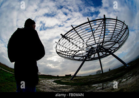 Un viandante si ferma ad ammirare la vista dell'Alone panopticon sulle colline sopra Haslingden, Lancashire come maltempo in rotoli. Foto Stock