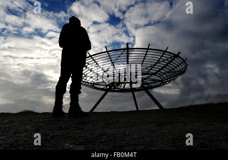 Un viandante si ferma ad ammirare la vista dell'Alone panopticon sulle colline sopra Haslingden, Lancashire come maltempo in rotoli. Foto Stock