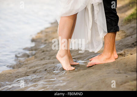 Amorevole coppia giovane costeggiata, baciare sulla spiaggia al tramonto Foto Stock