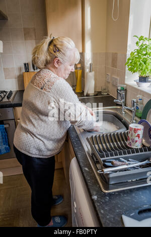 Lavorato a maglia,una signora anziana in cucina lavaggio fino Foto Stock