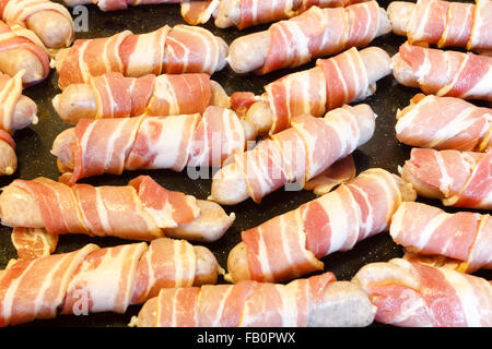 Tradizionale cibo di Natale di salsicce avvolto in pancetta, su un vassoio da forno. Inghilterra, Regno Unito Foto Stock