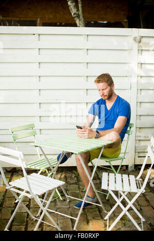 Giovani redhead Uomo con telefono cellulare in cafe Foto Stock