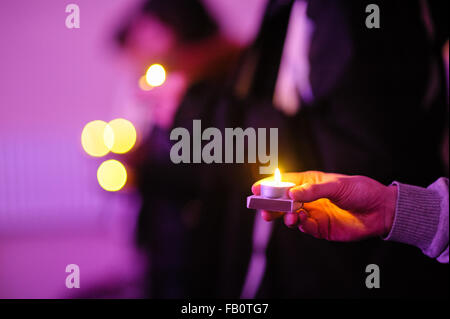 Mano che tiene la luce di una candela. Simbolo di speranza, pace e amore Foto Stock