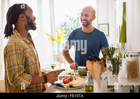 Smiley coppia omosessuale di bere vino in cucina Foto Stock