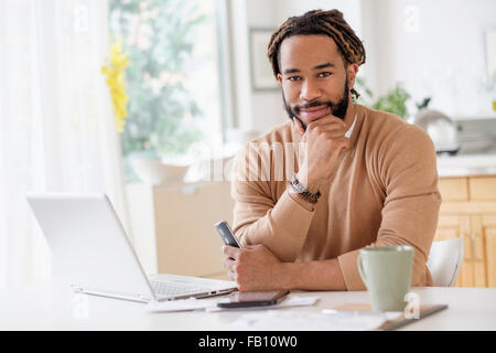 Ritratto di giovane uomo con notebook a tavola Foto Stock