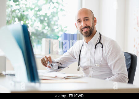 Ritratto di smiley medico che lavorano con il computer portatile alla scrivania in ufficio Foto Stock
