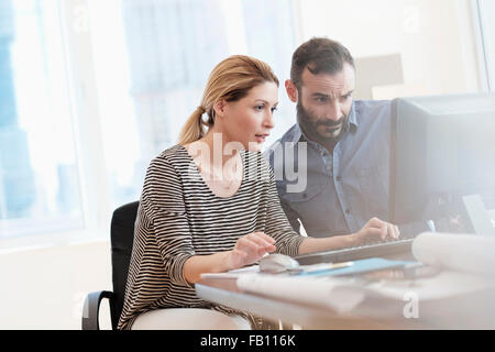 Uomo e donna che guarda al computer in ufficio Foto Stock