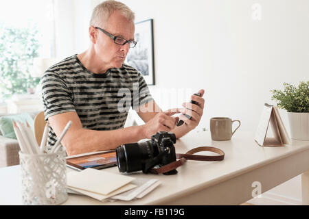 Uomo in ufficio a casa utilizza lo smartphone Foto Stock