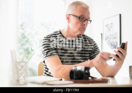 Uomo in ufficio a casa utilizza lo smartphone Foto Stock