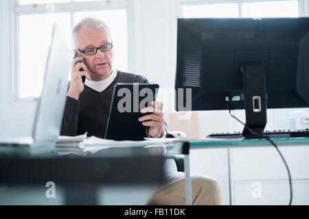 Uomo in ufficio utilizzando lo smartphone e tablet Foto Stock