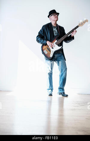 Uomo a suonare il basso chitarra in stanza vuota Foto Stock