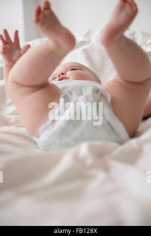 Baby girl (12-17 mesi) disteso con le gambe in alto Foto Stock