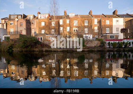 Riflessioni nel Grand Union Canal. Case a schiera in seduta il sole invernale si riflettono nell'acqua del Grand Union Canal. Foto Stock