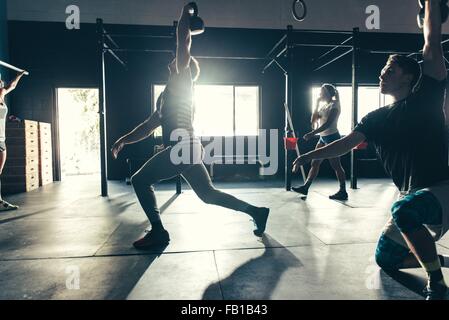 Le persone in formazione con kettlebell in palestra Foto Stock