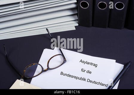 Asylantrag auf Behördenschreibtisch mit vielen Ordnern Foto Stock