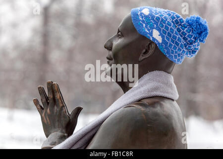 Statua di Sri Chinmoy permanente sulla banca del fiume di Vltava con un cappello e una sciarpa intorno al suo collo in una fresca snowy Praga Repubblica Ceca Foto Stock