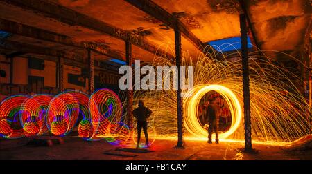 L uomo e la donna la creazione di multi-colore e golden scintilla sentieri di luce in edificio abbandonato Foto Stock