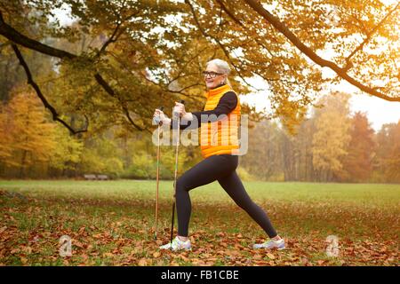 Femmina Senior Nordic Walker esercizio in posizione di parcheggio Foto Stock