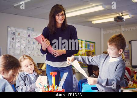 Insegnante femmina con bambini disegno nella scuola elementare classroom Foto Stock
