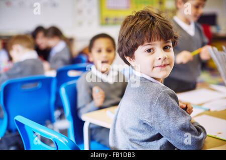 Ritratto di ragazzo guardando sopra la sua spalla nella scuola elementare classroom Foto Stock
