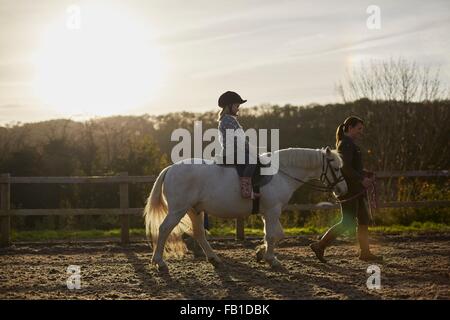 Istruttore ragazza leader di cavalcare pony equestre in arena Foto Stock