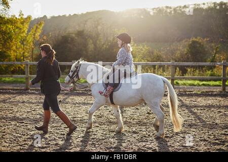 Istruttore ragazza leader di equitazione pony bianco in arena equestre Foto Stock