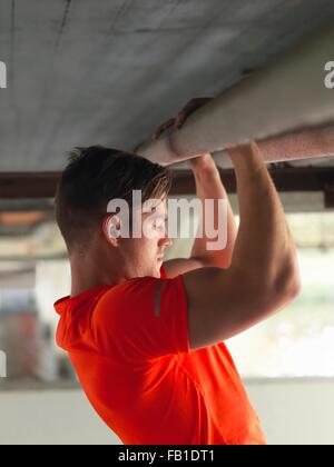 Giovane uomo facendo tirare ups sotto il ponte Foto Stock