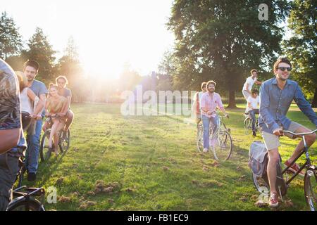 Righe di festa adulti arrivano in posizione di parcheggio per le biciclette al tramonto Foto Stock