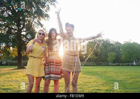 Ritratto di tre donne giovani amici stessi di incarto in streamers a parte in posizione di parcheggio Foto Stock