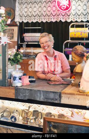 Ritratto di felice donna matura dietro vintage shop counter Foto Stock