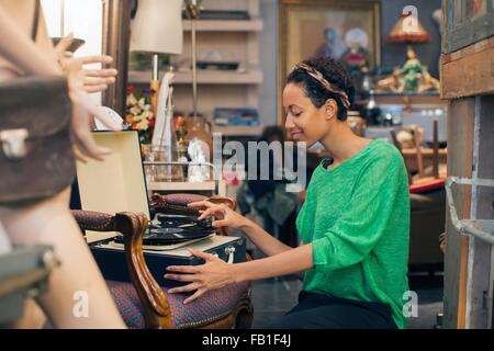 Giovane donna la riproduzione di dischi in vinile in negozio vintage Foto Stock