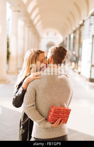 Giovane uomo nascondere regalo di Natale per la fidanzata in Covent Garden di Londra, Regno Unito Foto Stock