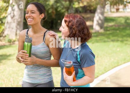 Angolo di alta vista di giovani donne a spasso di indossare abbigliamento sportivo portare bottiglie di acqua sorridente Foto Stock