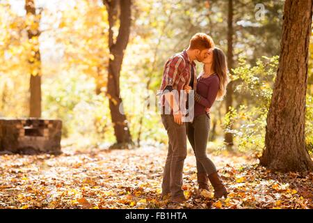 Coppia giovane kissing nella foresta di autunno Foto Stock