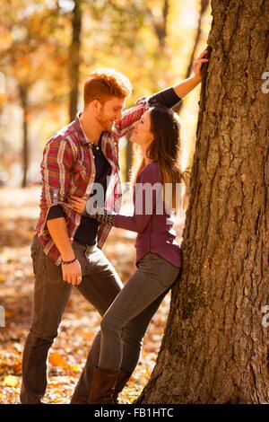 Romantico coppia giovane appoggiata ad albero nella foresta di autunno Foto Stock