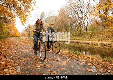 Felice coppia giovane escursioni in bicicletta lungo il fiume in autunno Foto Stock